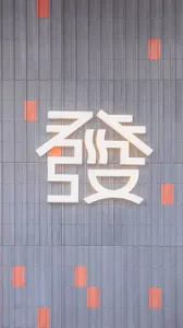 A contemporary Asian building with a large white sign featuring modern design and orange accents, set against a urban backdrop