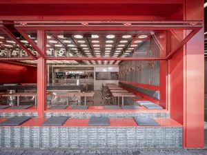 A warm and inviting restaurant with red and white walls, dining tables, and comfortable seating, well-lit for a cozy ambiance