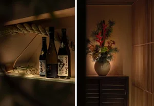 一張桌子上擺放著一瓶紅花與數瓶酒瓶整齊排列，營造溫馨舒適的氛圍