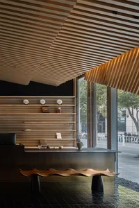 Warm and inviting hotel lobby with wooden walls and ceiling, featuring two couches, potted plants, and a dining table