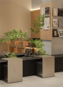A modern interior design showroom with a large rock garden, potted plants, and comfortable seating arrangements