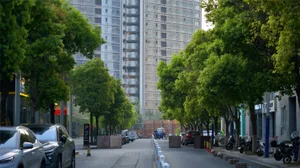 熱鬧的城市街景，包含高樓大廈、樹木、汽車、機車與行人