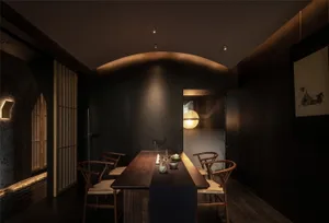 A cozy dining area with a wooden table surrounded by chairs, featuring a vase, bowls, and a cup, creating a warm and inviting atmosphere
