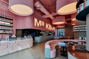 A modern restaurant interior with pink walls and ceiling, featuring dining tables and chairs in a comfortable and inviting atmosphere