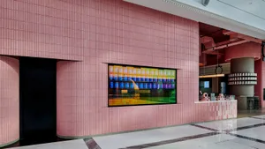 A modern interior design showroom featuring a large display of various bottles on a wall, arranged in rows, with pink walls adding a touch of warmth to the space