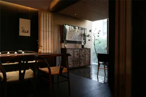 A cozy living area with a dining table surrounded by chairs, a TV on the wall, and a potted plant, creating a warm and inviting atmosphere