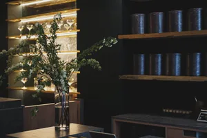優雅展廳中，黑桌子上擺放花瓶與酒杯，背景環繞其他桌椅