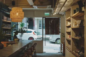 Dining area with chairs and tables, potted plants, and a view of a car outside through a window