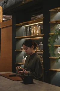 一位女性站在裝滿瓶子的展示櫃前，位於氛圍時尚的現代零售空間
