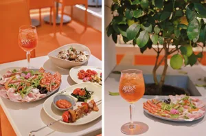 A warm and inviting dining area in an orange-themed restaurant with plates of food and a wine glass on a table, accompanied by a potted plant
