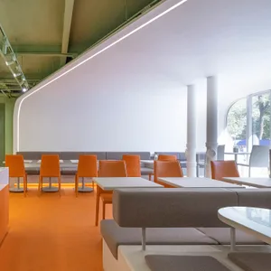 Modern restaurant interior with white walls, multiple tables, couches, and chairs, creating a clean and inviting atmosphere