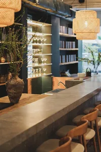 Elegant bar area with a counter, sink, wine glasses, and bottles, adjacent to a dining table in a sophisticated restaurant setting