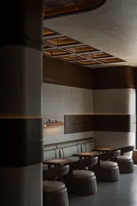 Dimly lit restaurant interior with wooden walls and floors, featuring dining tables and chairs