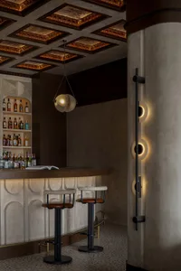 Cozy bar area with a wooden counter, several chairs, and a selection of liquor bottles