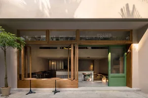 Modern restaurant interior with wooden elements, green accents, and ample seating options