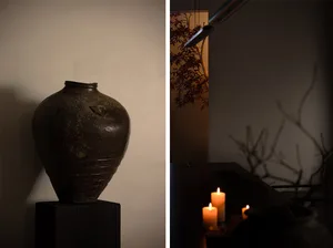 A cozy room with a candlelit atmosphere, featuring a vase on a table and a warm glow