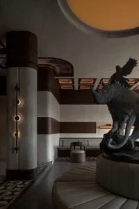 A living room with a table holding a rhino and bird statue, a chair, and an elegant atmosphere