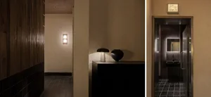 Dimly lit bathroom with a black vase and wall lights, creating a moody atmosphere