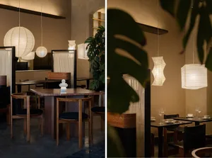 A modern restaurant interior with wood elements, potted plants, and multiple dining tables and chairs, creating an inviting and comfortable atmosphere