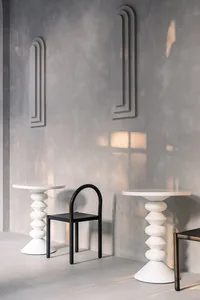 Two modern tables and chairs placed on a grey wall in a minimalist interior design setting