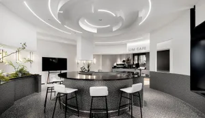 A cozy cafe with a circular bar surrounded by chairs and tables, featuring potted plants and an inviting atmosphere