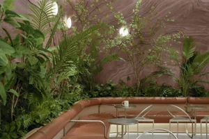 Cozy living and dining space with stone walls, two couches, chairs, coffee tables, and plants, creating a warm and inviting atmosphere