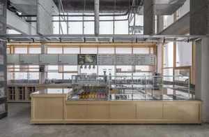 Modern restaurant interior with a large counter, dining table, appliances, and bottles, featuring ample space for customers