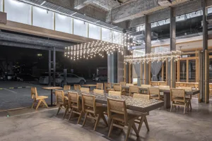 A modern restaurant interior with wooden tables and chairs, dimly lit for a cozy ambiance