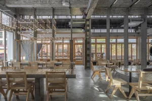 Open modern restaurant interior with wooden tables, chairs, and well-designed lighting creating a warm and inviting atmosphere