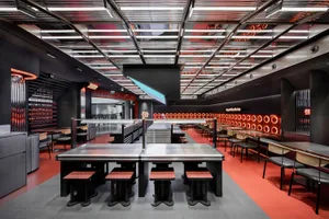 Industrial kitchen dining space with a large dining table, multiple chairs, and benches, featuring a functional and practical atmosphere