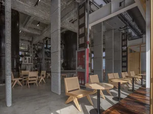 Industrial cafe with scattered seating areas featuring chairs and dining tables in a large open space
