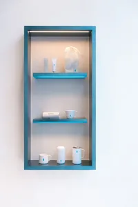 A glass display case filled with three cups, two bottles, and two handbags, arranged in a well-organized and tidy manner
