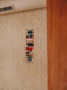 A unique piece of artwork resembling a stained glass window mounted on a wall in a living area