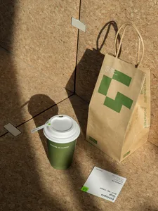 A casual indoor scene with a wooden table, a coffee cup, and a brown paper bag, creating a warm and inviting atmosphere