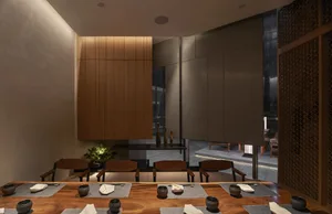 A restaurant interior with wooden floors and walls, featuring dining tables, chairs, and potted plants