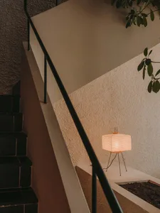 A cozy interior staircase with wooden steps and a metal railing, lit by a small lamp at the bottom
