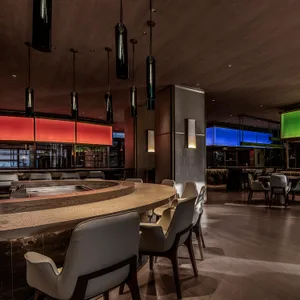 Warm and inviting restaurant interior with wooden floors and walls, comfortable seating, and dining tables with bottles on some of them