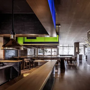 Warm and inviting restaurant dining space with wooden floors, a large dining table, and potted plants