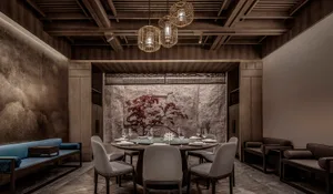 A sophisticated dining area with a round table, wine glasses, and fine china, set in a restaurant with artwork on the walls