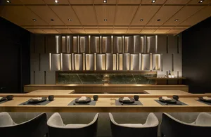 Sophisticated restaurant interior with a large dining table, wooden chairs, and fine china and cups