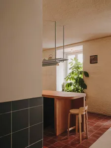 cozy kitchen with wooden cabinets, a dining table, and a potted plant, featuring a sink and a hanging pot rack
