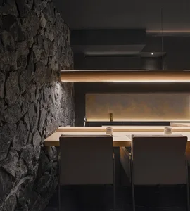 A modern kitchen with a long wooden dining table surrounded by chairs, creating an inviting atmosphere for gatherings and meals
