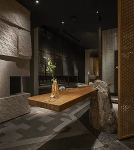A warm and inviting living area with a wooden table, two chairs, a potted plant, and a cozy seating arrangement