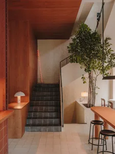 A hotel staircase with wooden steps and a black railing, accompanied by two chairs for guests to rest or wait