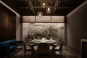 Dining area with a round table, stone walls, and fine china and wine glasses
