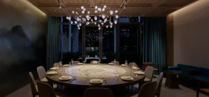 A luxurious dining area with a round glass table, wine glasses, and multiple cups, set in a refined atmosphere