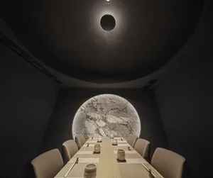 Dark dining area with a round table, chairs, and a dome, set up for a meal with several bowls on the table