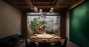 A modern dining space with a round table surrounded by chairs, a centerpiece featuring a tree, and a sophisticated atmosphere