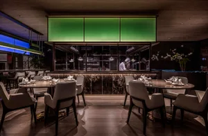 Warm and inviting restaurant interior with wooden elements, green and brown tones, and multiple tables set with various items