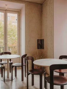 well-lit restaurant interior with tables, chairs, and potted plants, featuring a mix of brown and white tones